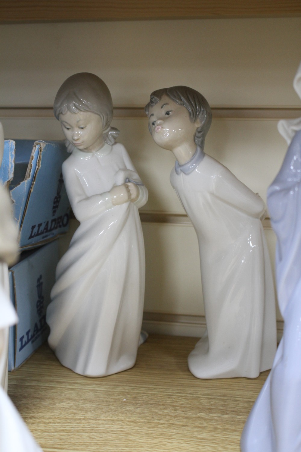 Four Lladro figures of children in their nightdresses, largest 24cm, three similar Nao figures, largest 27cm and a Royal Doulton figure